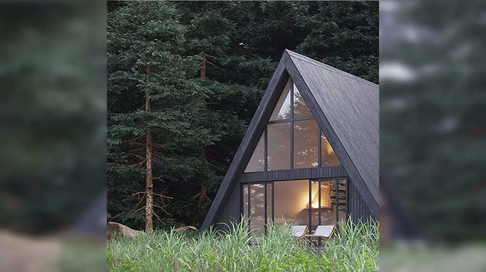 Cozy A-frame cabin in forest evening setting with warm lighting